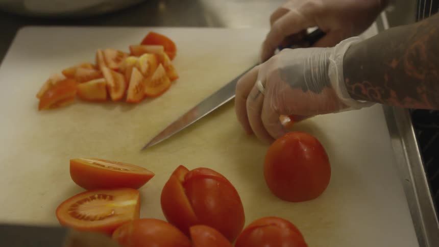 A person is cutting tomatoes on a cutting board