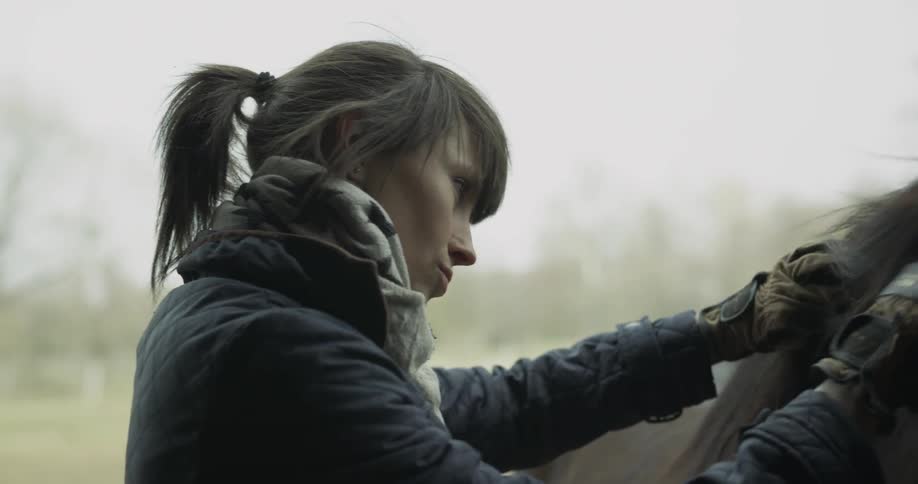 A woman brushes the mane of a horse
