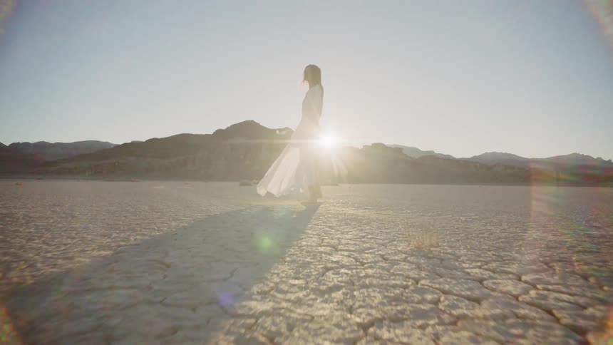 Woman stands outside in the desert on a sunny and windy day