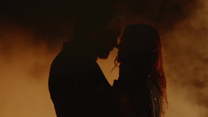 A man and woman are holding each other by a fire