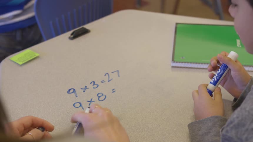 Woman and child work on math at desk in classroom