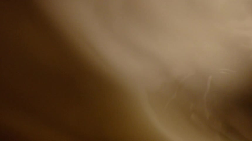 Paint is poured into liquid glossy sparkly brown paint or perhaps it is honey but the light reflects and shines