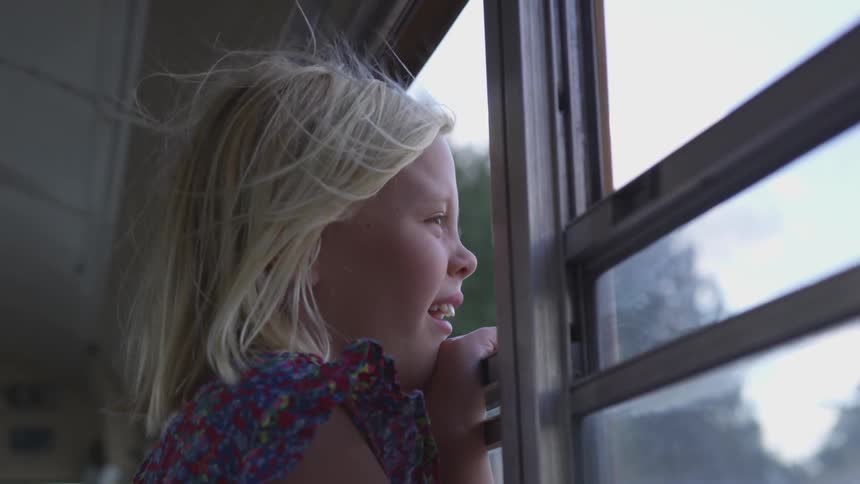 Girl laughs as she looks out open bus window