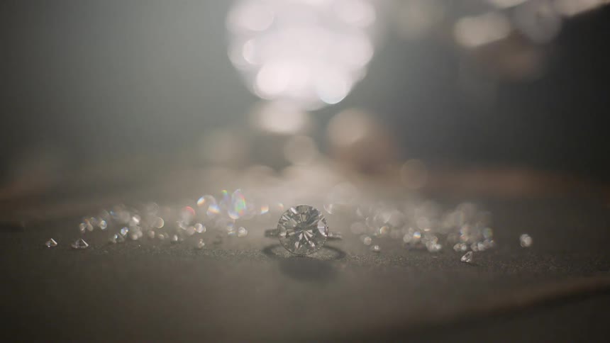 Light shines behind a ring and a pile of jewels