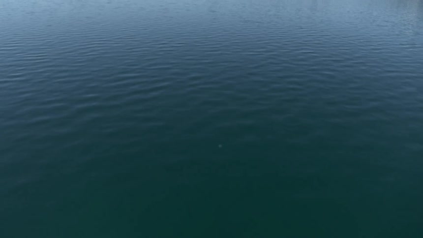 Beautiful clear water shows rocks and sand at the bottom with mountains on the horizon