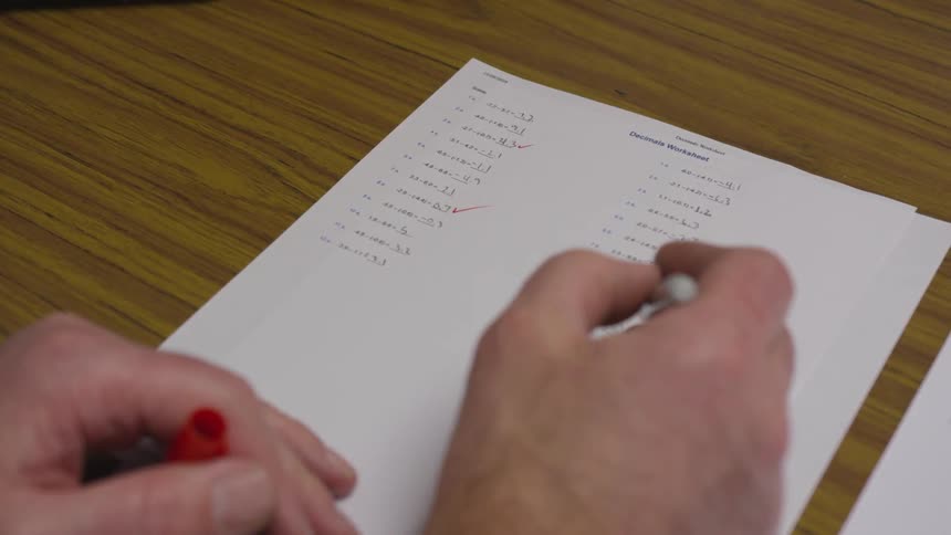 A person making check marks on a piece of paper