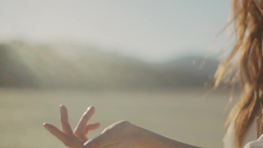 A woman holds out her hand in a sunny desert