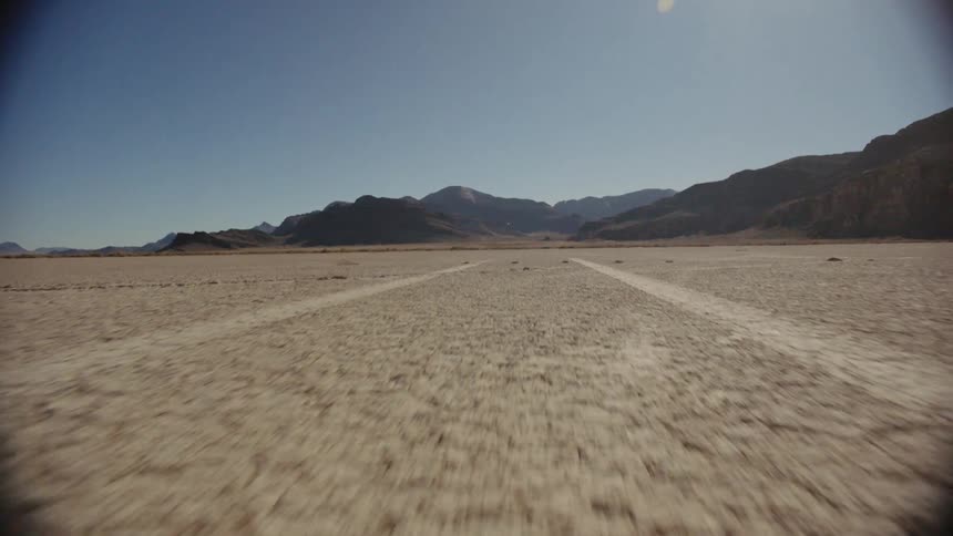 There is a dirt road by some mountains
