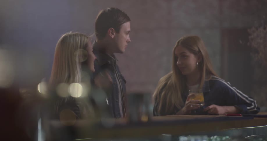 Three people are talking and drinking at a bar