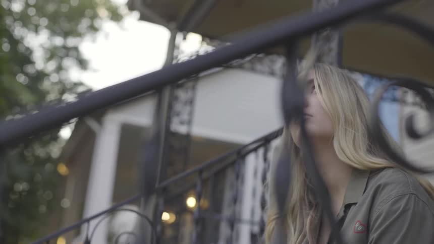 A woman is sitting down outside and looking up