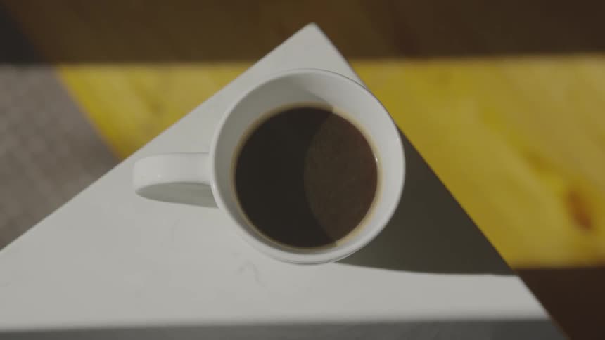Round white ceramic mug filled with black liquid on white table