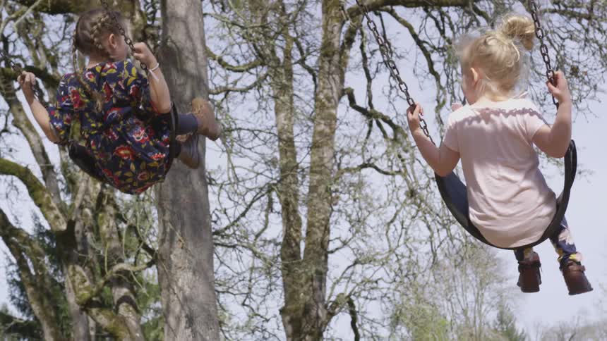 Two children swing back and forth at noon