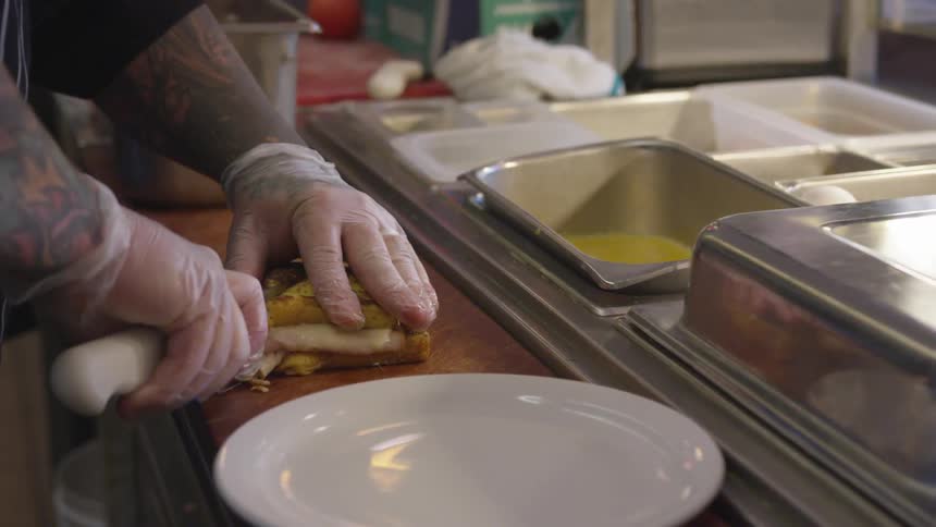 A chef cuts a sandwich in half into triangles