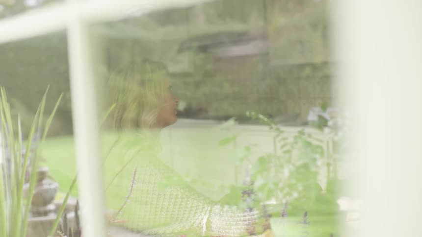 A woman can be seen through a window talking inside a kitchen at day