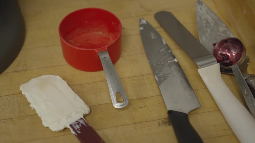 Dirty kitchen utensils including measuring cup, spatula and knife