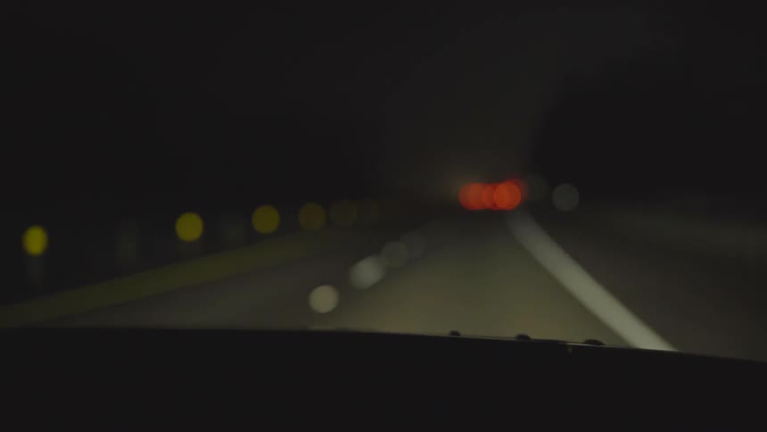 A car drives down a dark road at night