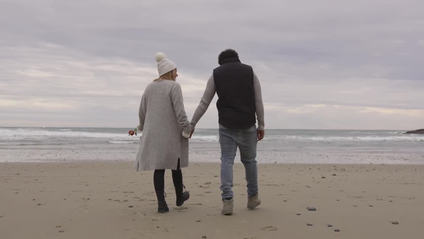 Man and woman walking hand in hand on a beach