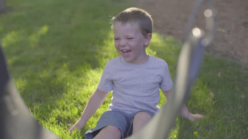 A child sitting in grass and laughing