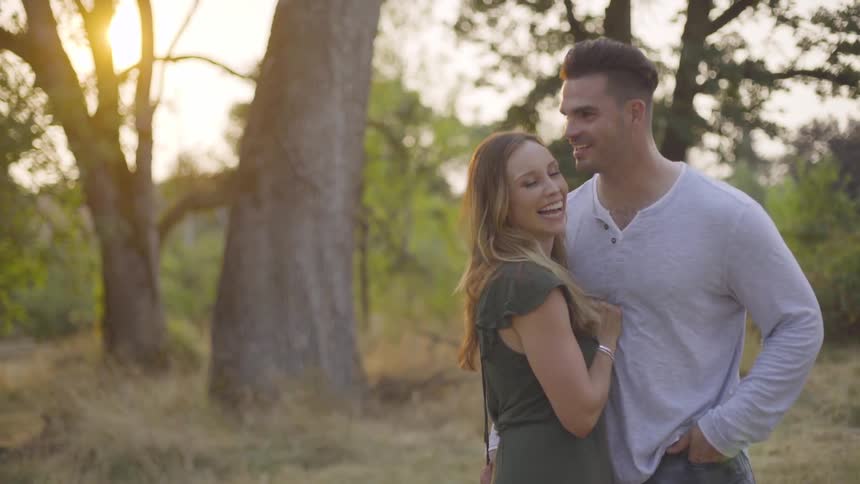 Young couple kisses and smiles in forest