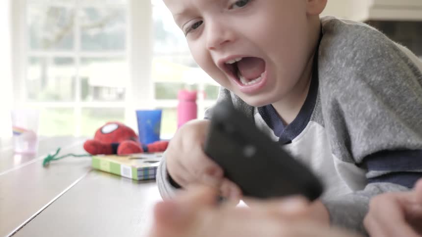 A little boy tries to take a phone from another boy