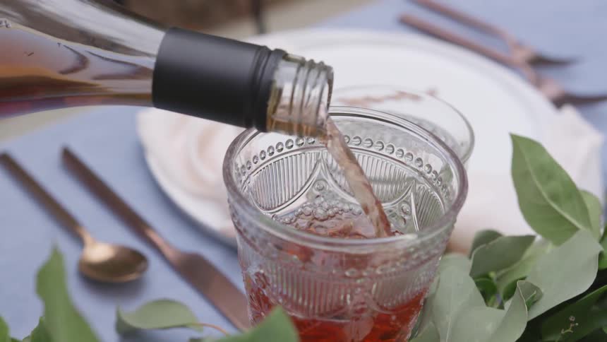 Wine is poured into a glass on a set table