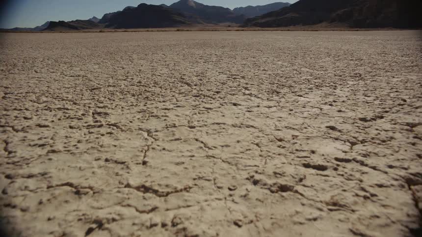 A vehicle driving on a cracked lake bed