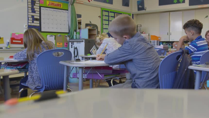 A boy looks up from his desk in a school classroom