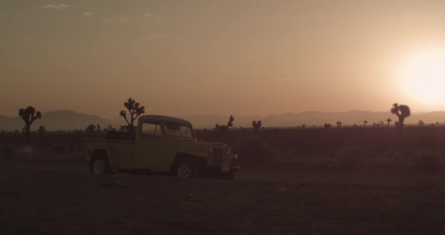 An old pick up truck parked in the desert at sunset