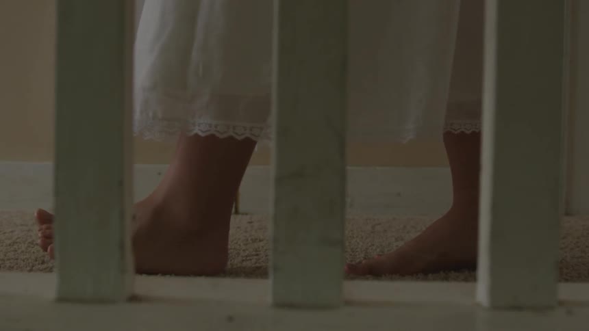 A barefoot woman in a sleeping gown walking near a railing
