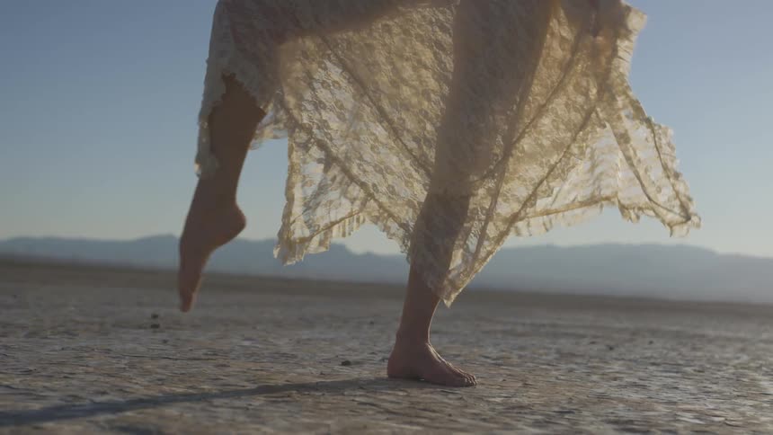 A woman in a lace skirt dances in a desert