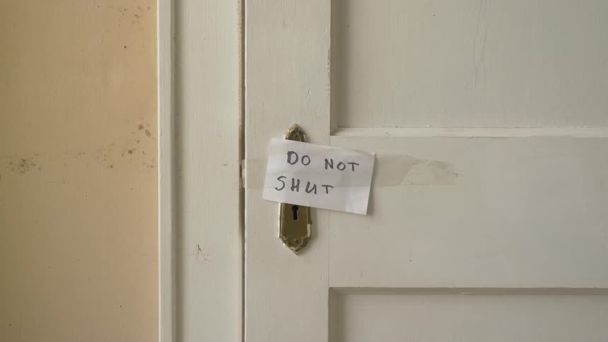 Do not shut is written on a piece of paper over the missing handle of a door with a old fashion key hole for skeleton keys