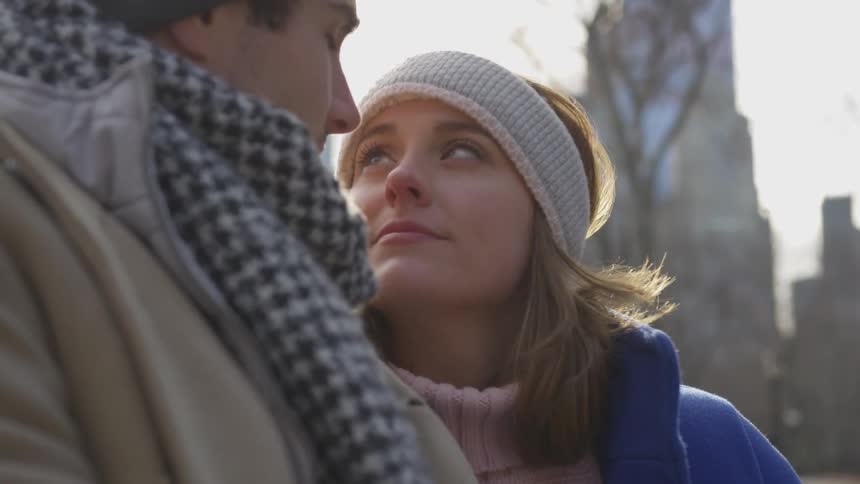 Man and woman look into each other's eyes in a park setting