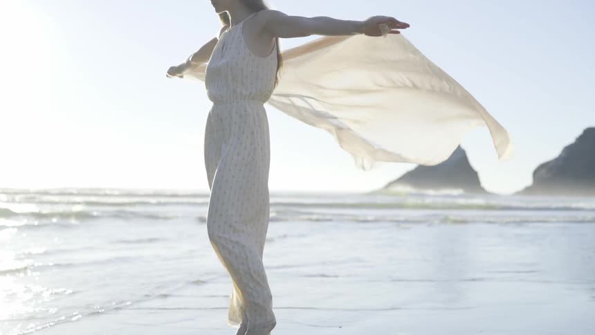 A woman holds a shaw behind her in the wind