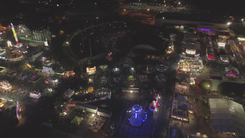 A carnival at night with spinning lights rides and meal carts