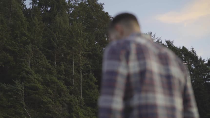 A man stands in front of a forest