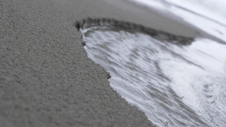 Water washing away sand at a beach