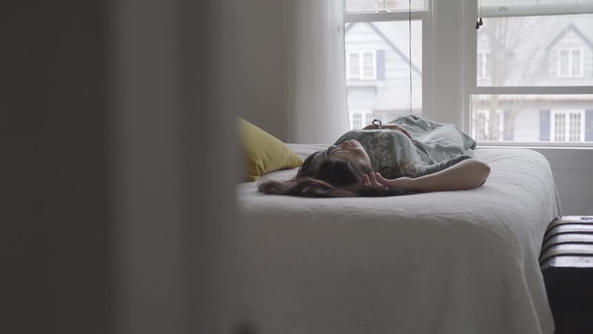 A woman is laying down on a bed