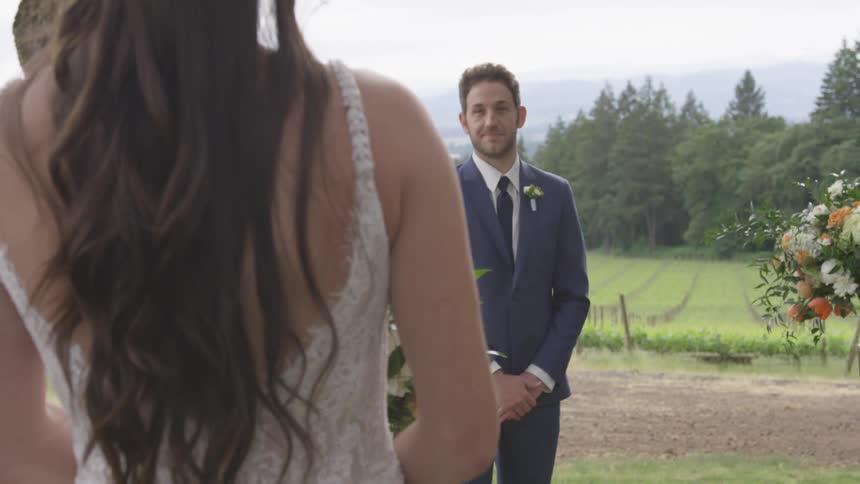 A woman in a wedding dress is walking towards a man