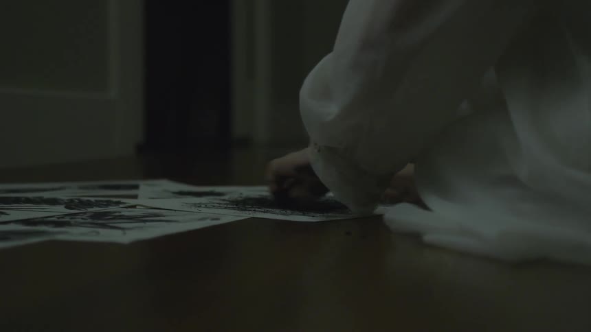 A child scribbles on a piece of paper with a black crayon