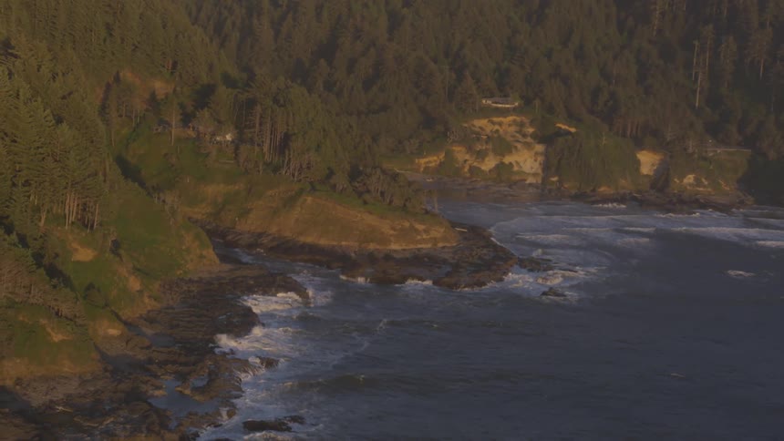 Waves breaking on a beach by tree and shrub lined hills