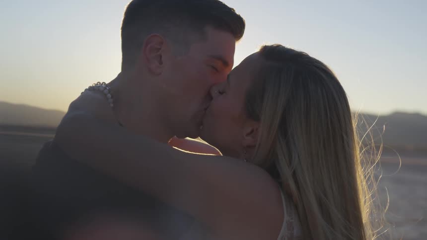 A woman and man kiss in the sunlight