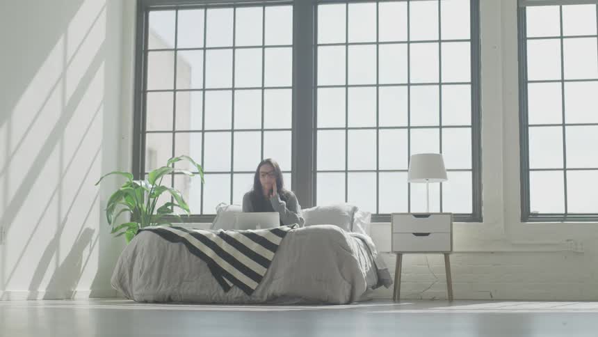Woman sitting with her laptop in bed