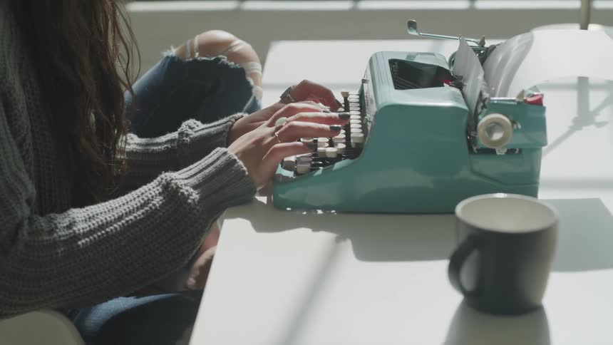 A woman types on an antique typewriter
