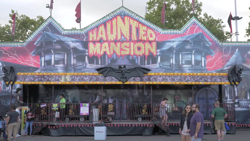 People walk past a ride at a fair