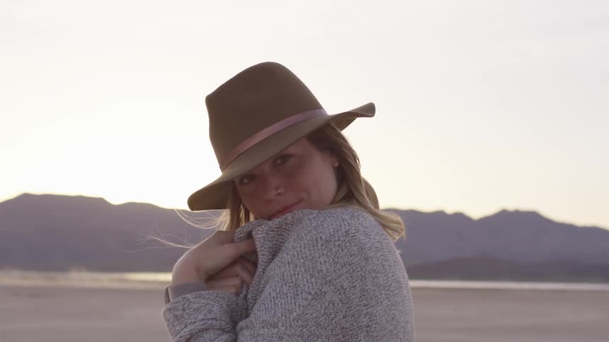 Woman wears hat and lowers sweater from covering her mouth