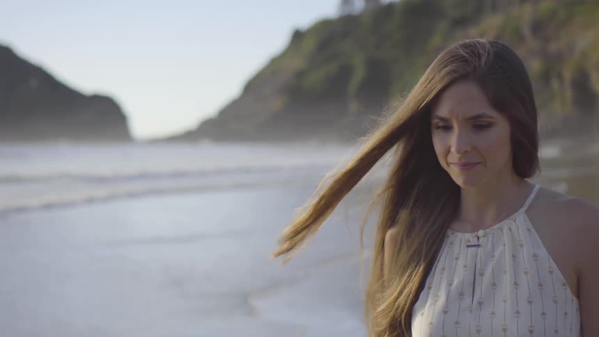 Woman with long hair walks along a beach