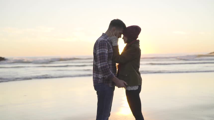 A man and woman kissing at the beach