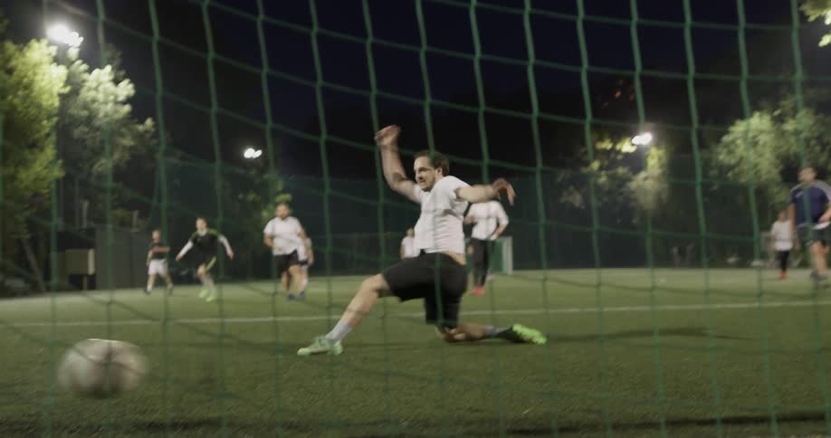 A soccer player tries to block another player from making a goal but misses