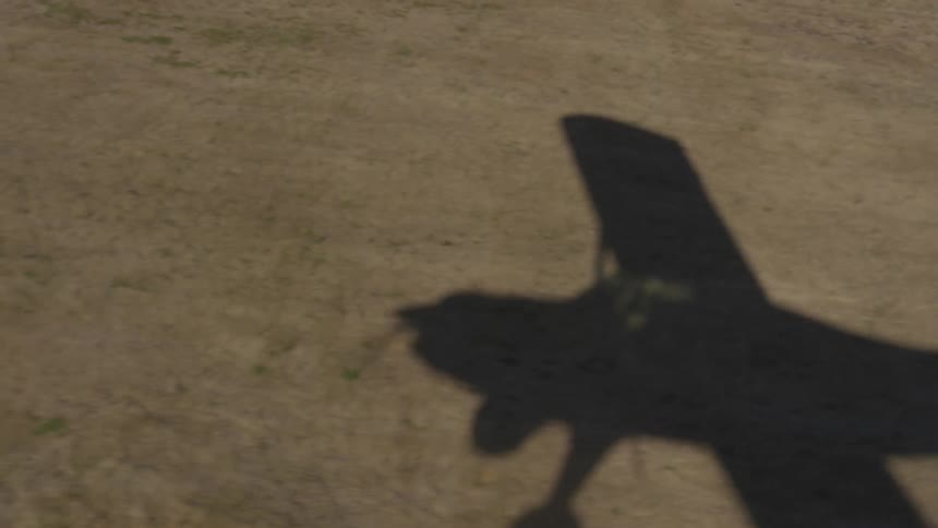 A plane creates a shadow on the ground