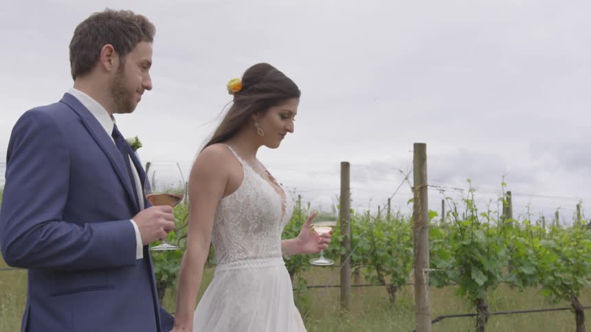 A man and woman carrying wine out into a field of grapes